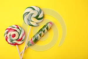 Colorful lollipops on yellow background, flat lay. Space for text