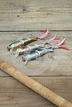 Colorful lures with the fishing rod on the wooden pier
