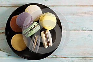 Colorful macaron cookies on black color plate. Sweet and colorful French macarons