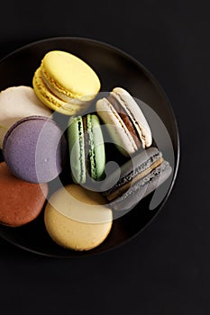 Colorful macaron cookies on black color plate. Sweet and colorful French macarons