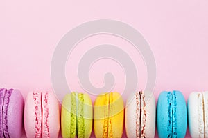 Colorful macaron or macaroon on pink pastel background top view. Flat lay composition.