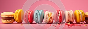 Colorful macarons aligned on pink background.