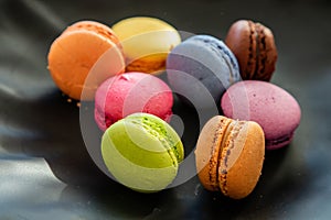 Colorful macarons on black background, close up view