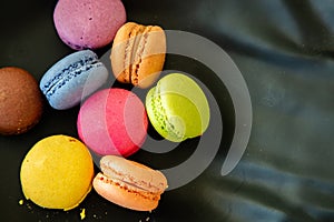 Colorful macarons on black background, close up view