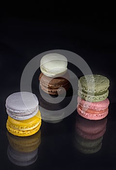 Colorful macarons on black background with reflection
