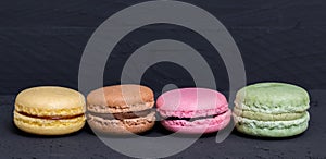 Colorful macarons on a black wood