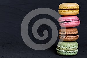 Colorful macarons on a black wood