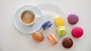 Colorful macarons and coffee cup on white background, close up view