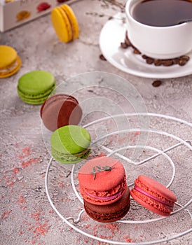 Colorful macarons and cup of coffee over on gray background