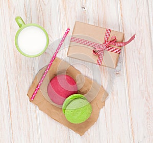 Colorful macarons, cup of milk and gift box