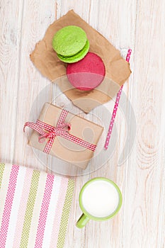 Colorful macarons, cup of milk and gift box