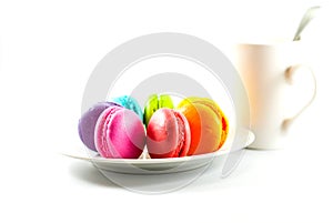 Colorful of macarons on a white plate and white coffee cup on a white background, selective focus
