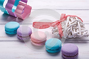 Colorful macaroons with white wooden heart ovewhite wooden background. valentine`s day