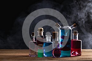 Colorful magic potion bottles on wooden table. Medieval alchemist laboratory with various kind of flasks.