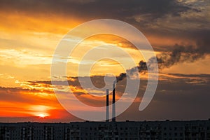 Colorful Magic Sunset. Roofs of city houses during sunrise. Dark smoke coming from the thermal power plant pipe