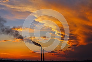 Colorful Magic Sunset. Roofs of city houses during sunrise. Dark smoke coming from the thermal power plant pipe