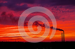 Colorful Magic Sunset. Roofs of city houses during sunrise. Dark smoke coming from the thermal power plant pipe