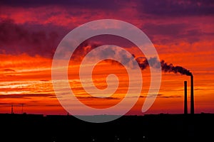 Colorful Magic Sunset. Roofs of city houses during sunrise. Dark smoke coming from the thermal power plant pipe