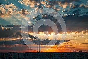 Colorful Magic Sunset. Roofs of city houses during sunrise. Dark smoke coming from the thermal power plant pipe