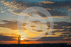 Colorful Magic Sunset. Roofs of city houses during sunrise. Dark smoke coming from the thermal power plant pipe