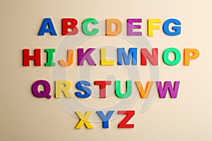 Colorful magnetic letters on beige, flat lay. Alphabetical order