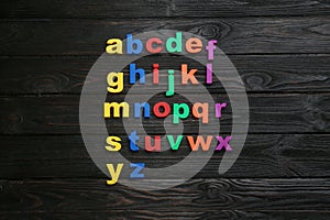 Colorful magnetic letters on black background, flat lay. Alphabetical order