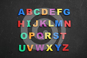 Colorful magnetic letters on black stone background. Alphabetical order