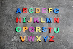 Colorful magnetic letters on grey background, flat lay. Alphabetical order