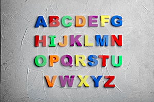 Colorful magnetic letters on light grey stone background. Alphabetical order