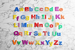 Colorful magnetic letters on marble background, flat lay. Alphabetical order