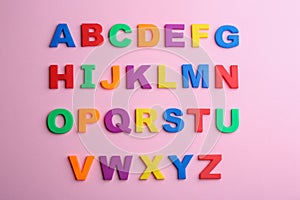 Colorful magnetic letters on pink background. Alphabetical order