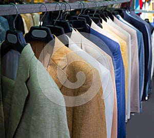 Colorful male suits in row in a hanger