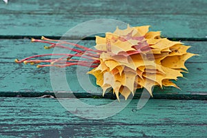 Colorful maple leaves in the autumn on a blue-green colored bench in the park