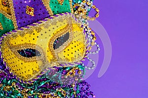 Colorful Mardi Gras mask on purple background with beads