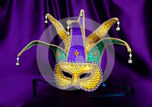 Colorful Mardi Gras mask on purple background with beads