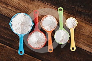 Colorful measuring cups with flour on wooden table