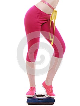 Colorful measuring tape on woman body, fit girl measuring her waistline standing on scale