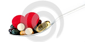 The colorful medical supplement and drug pills with red heart in spoon , pharmaceutical cardiology drugs for heart health care