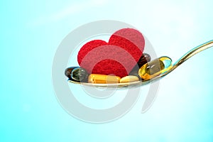 the colorful medical supplement and drug pills with red heart in spoon , pharmaceutical cardiology drugs for heart health care