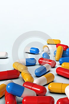 Colorful medicine capsules on white background, vertical