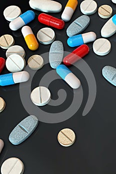 Colorful medicine pills on dark background, vertical