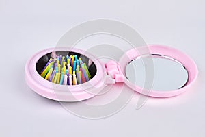 Colorful mini folding hair brush with mirror on white background.