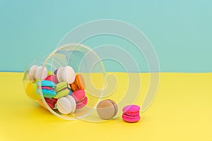 Colorful mini macarons in plastic cup on yellow table