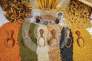 Colorful mixed cereals and legumes: rice, pasta, lentils, beans, chickpea on white background. Top view. Empty space for text