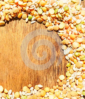 Colorful mixed cereals and legumes: rice, peas, lentils and pearl barley on a wooden background. View from above. Empty space for