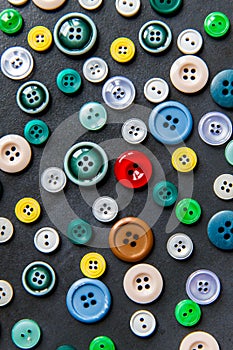 Colorful mixed sewing buttons on black background, flat lay. Top view