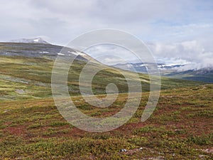 Colorful mountain Sanjartjakka at turn-off to peak from Kungsleden hiking trail. Beautiful wild Lapland nature landscape with birc