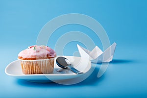 Colorful muffin on saucer with paper boat
