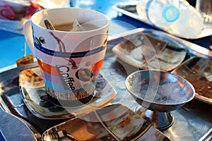 A colorful mug  with a hot beverage and a saucer on the side presented in a tray
