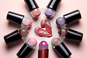 Colorful nail polish bottles forming a heart on a pink backdrop